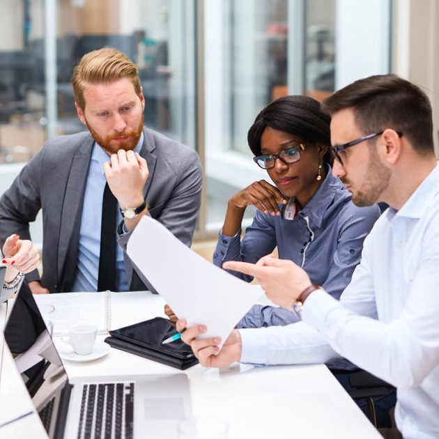 business-transformation Photo of a team discussing business strategies around a document.